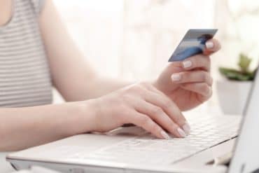 femal holding a credit card and using computer